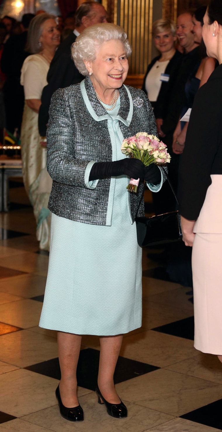 Image: Britain's Queen Elizabeth receives a posy at a reception at which she signed the Commonwealth Charter at a reception at Marlborough House in central London